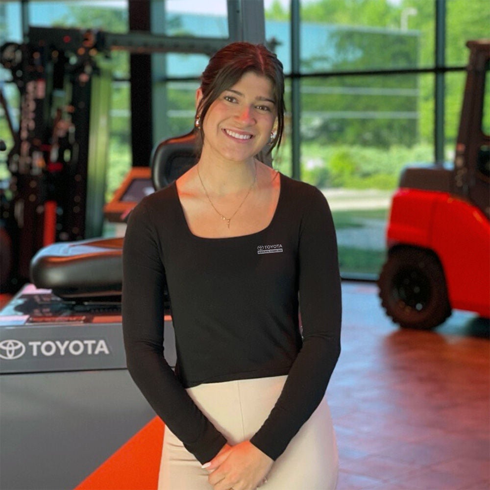 toyota female intern smiling in front of forklift